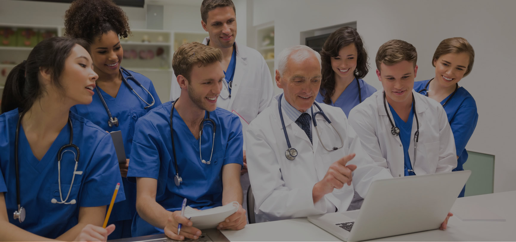 Medical students and a professor at a laptop